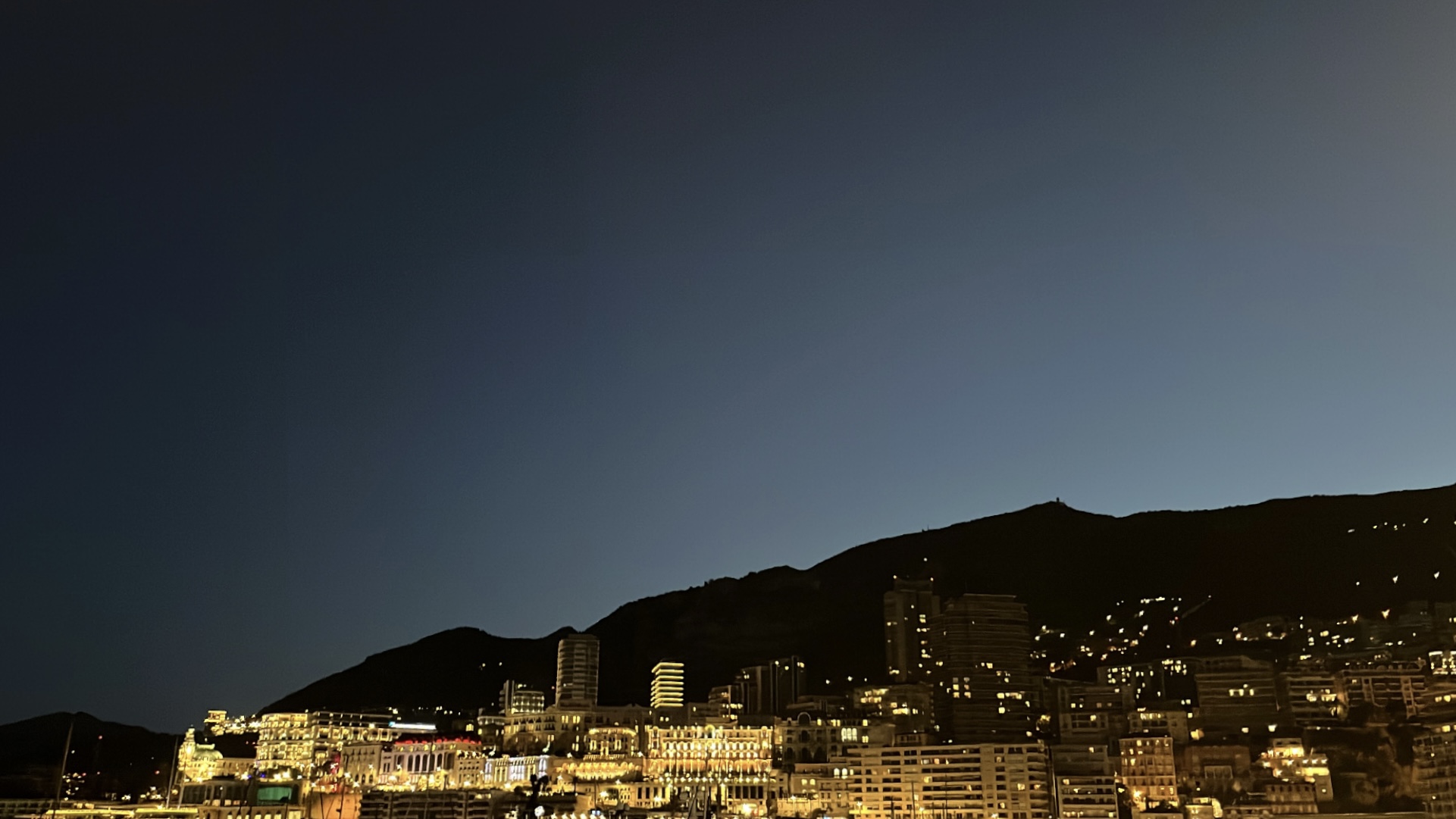Din Tanovic — Monaco skyline glowing gold at twilight under a deep blue sky