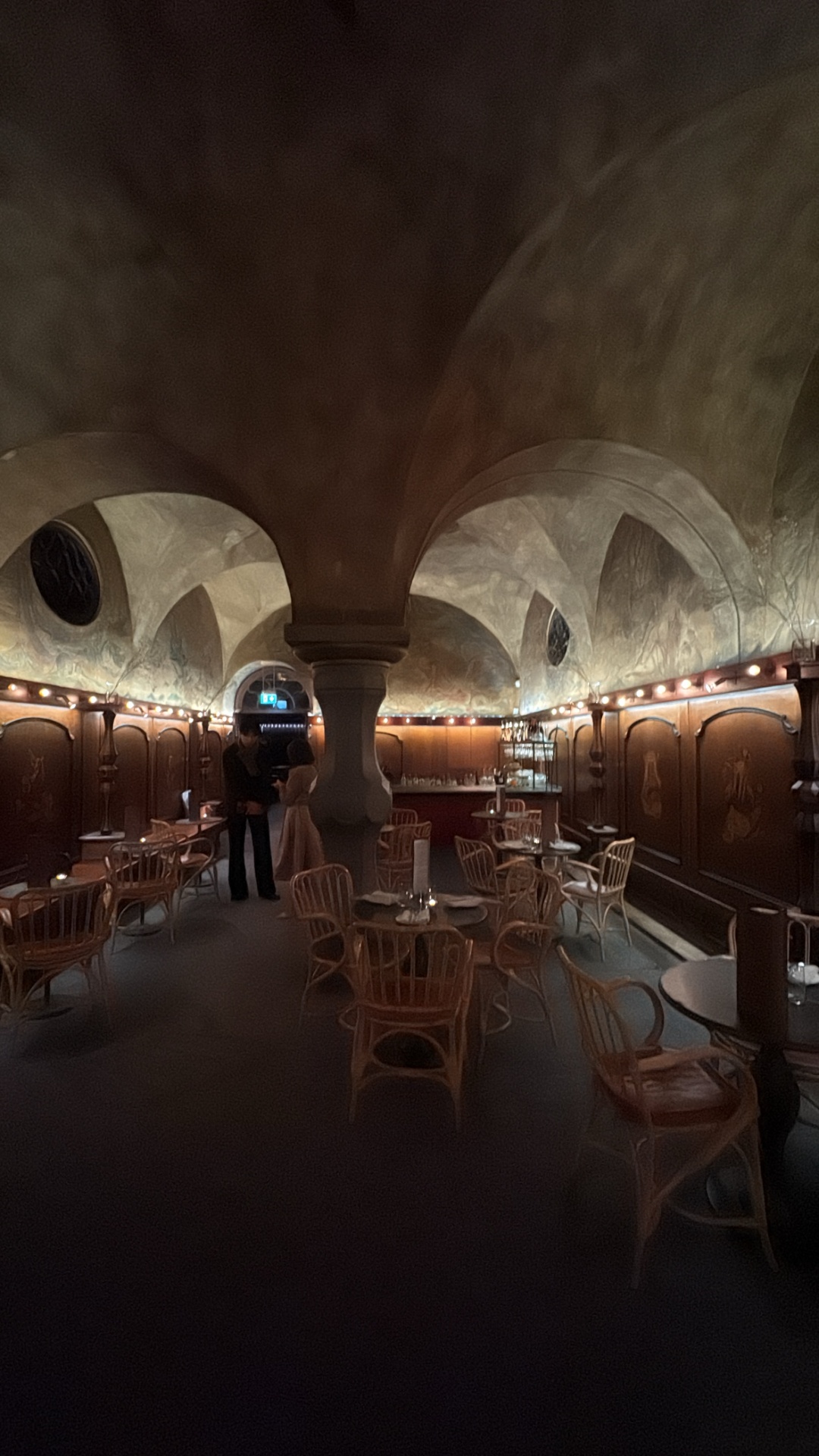 Din Tanovic — painted vaulted ceiling and rattan chairs of a candlelit Stockholm dining room