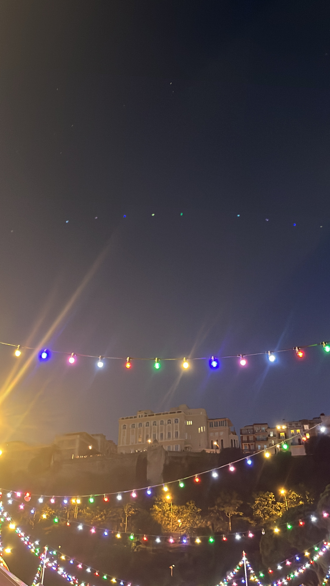 Din Tanovic — strings of colored festival lights above Monaco rooftops at night